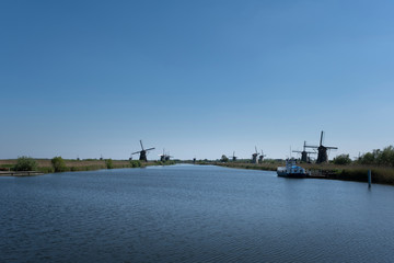 Fototapeta na wymiar Landscape with beautiful traditional dutch windmills near the water canals with blue sky and clouds reflection in water.