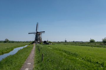 Landscape with beautiful traditional dutch windmills near the water canals with blue sky and clouds reflection in water.