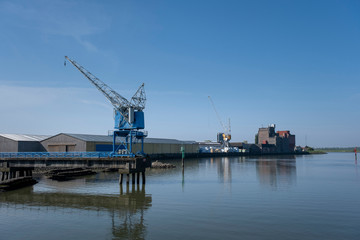 Fototapeta na wymiar Cranes near the river against blue sky. Industrial landscape, industrial zone.