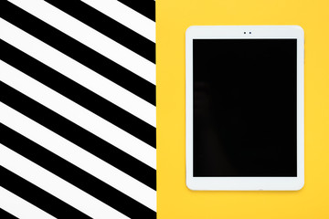 digital tablet with black touch screen display on yellow and white, black stripes background Flat lay Top view Mock up Creative modern composition