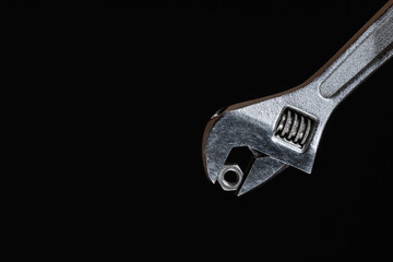 Wrench with conventional hex nut on black background close-up at an angle