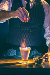 Bartender making sparkling Baileys comet cocktail on fire