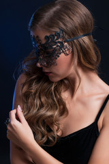 Fototapeta premium young pretty brunette woman in venetian lacy mask. close up portrait lacy mask. red lips make up. erotic passion woman image on black background