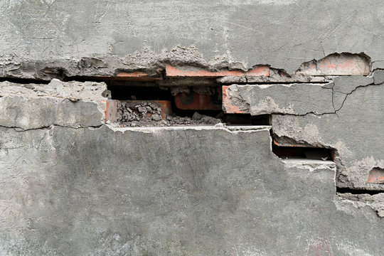 Crack in the brick wall of the house through the plaster in the form of steps with one brick missing close up