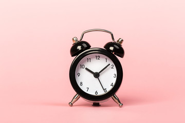 black retro alarm clock on a pink background,
