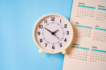 Fototapeta na wymiar analog white clock with calendar on blue paper background, flat lay, deadline concept