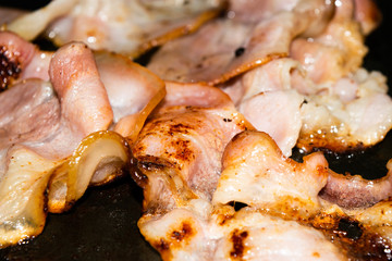 Obraz na płótnie Canvas Fried slices of raw bacon. Close up.