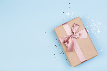 Gift or gift box and stars confetti on a blue table from above. Flat composition for birthday