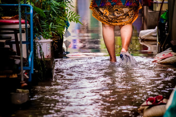 The feet of an Asian woman were walking through the flood.