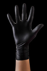 Hand in black gloves showing five fingers and palm isolated on black background