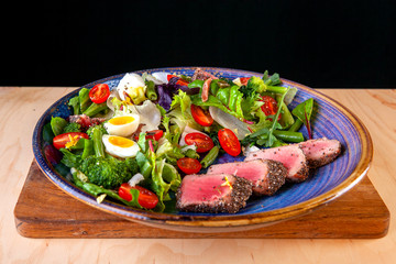 salad of tomato greens eggs and fish sliced on a plate