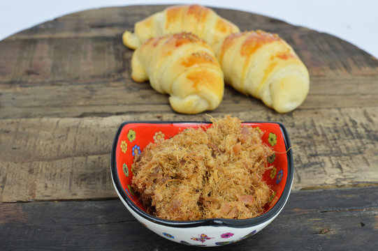 Fried Pork greaves, cracklings, duvan cvarci, in the ethno red bowl and pastry rolls(kiflice) in the background on the wooden plate.