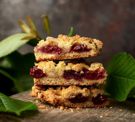 stack of square pieces of crumble pie with cherry on a wooden board