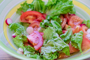 vegetable salad of tomato, cucumber, radish and lettuce seasoned with olive oil. healthy eating concept