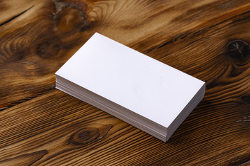 Fototapeta premium Stack of white business cards on brown wooden background