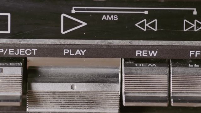 Man finger pressing some buttons on an old retro vintage cassette tape player: play, rewind, fast forward, stop
