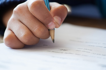 Close up image of a mixed race primary school learner writing in a workbook at school
