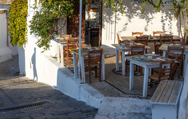 Fototapeta na wymiar Typical greek taverna with wooden furniture and vegetation hanging from roof in Lindos, island Rodes