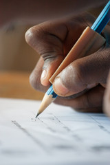 Close up image of a mixed race primary school learner writing in a workbook at school