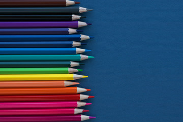 vertical row of multicolored pencils on dark blue background. Back to school and buying school supplies. Educational concept.