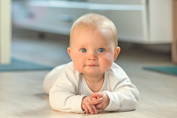 eight month old baby boy lying on the ground and looking at camera