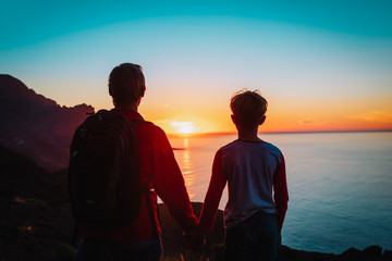 father and son travel in sunset mountains, family hiking in nature