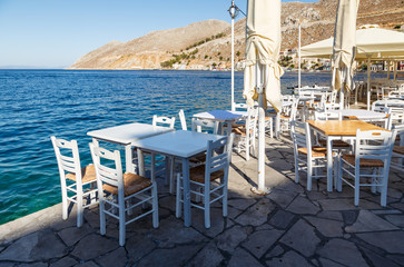 Tables in local traditional restaurant on coastal promenade of Symi town. Greece