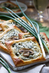 Puffs with cheese, spinach and mushrooms, served with wine and green onions. Rustic style.