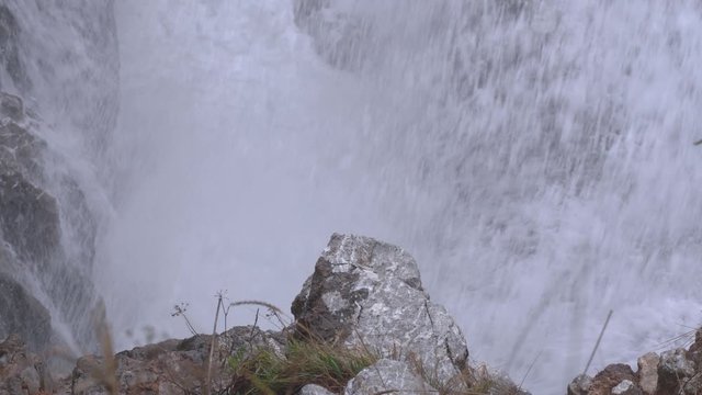 Mountain river rushes noisily among rocks, cold spray flying around, close up. Beauty and power of irrepressible natural elemental force in untouchable corners of planet, extreme travel and hiking.