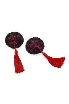Detailed shot of two nipple stickers decorated with black lace on the red base and red silk tassels. The pair of pasties is isolated on the white background. 