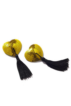 Detailed shot of two heart-shaped nipple stickers decorated with golden paillettes and black silk tassels. The pair of pasties is isolated on the white background. 