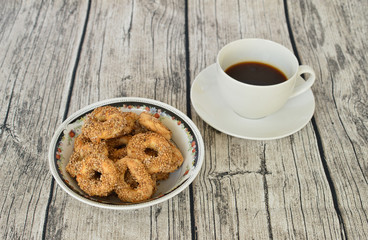 Traditional Turkish homemade salty ring cookies, tuzlu kurabiye, with sesame and cumin in a bowl and a cup of coffee 