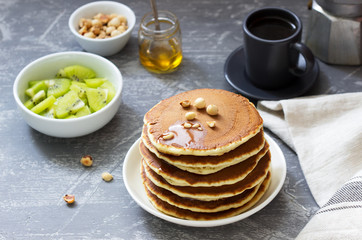 Vegetarian breakfast of pancakes, coffee, honey, nuts and fruits.