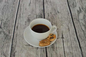 A white cup of black coffee with sesame pastry