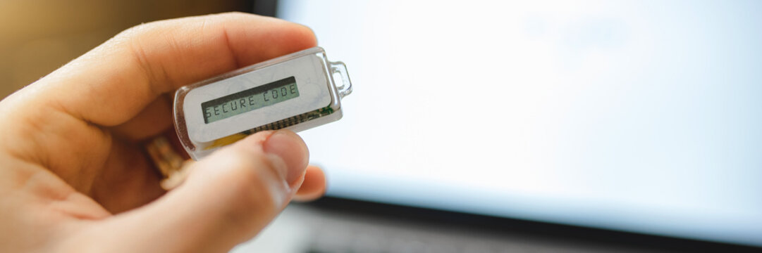 Horizontal banner and close up man hand holding a code generator. Online shopping with laptop computer. Internet home banking payment.
