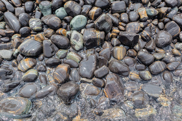 Beautiful wet black pebble stone beach shiny and smooth natural in tropical sea on coastline
