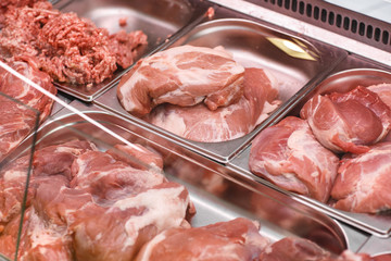 Heap of fresh meat food meat food background in supermarket store. Different types of raw meat in plastic boxes, leg of lamb on the bone, beef tail, beef neck, beef blade. Concept of farm and raw