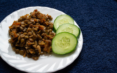 plate with lentils and cucumbers on a blue background