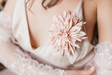 Brooch on the dress. A brooch made of a flower. A young girl in a light dress. Lingerie-style dress. selective focus.