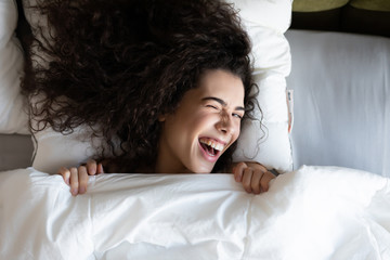Beautiful woman lies on white bed linen in soft morning light. Concept of happy family living,...