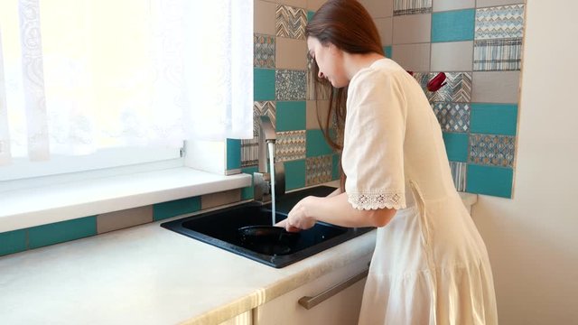 The ghousewife irl in the white dress washes the pan.