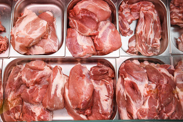 Heap of fresh meat food meat food background in supermarket store. Different types of raw meat in plastic boxes, leg of lamb on the bone, beef tail, beef neck, beef blade. Concept of farm and raw