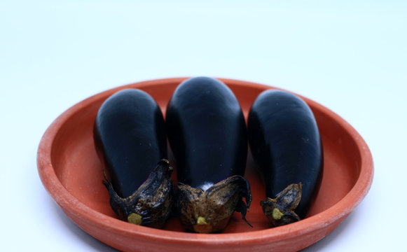 Nasubi or Japanese Eggplant on pottery plate, on white background.