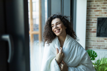 Beautiful woman standing in white blanket in light room, morning, relax time at home