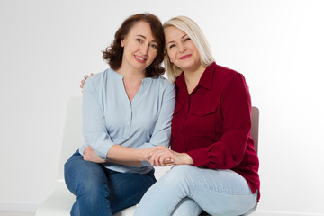Two middle aged women talking. Isolated white background. Women support women concept. Happy...