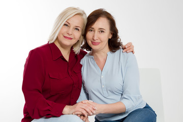 Happy menopause concept. Two healthy and beautiful middle aged women isolated on white background. Woman support woman. Closeup faces and skincare makeup.