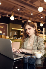 Confident young woman photographer in smart casual wear working on laptop