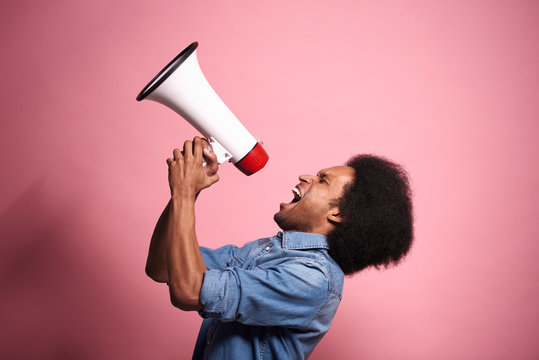 Young African man shouting loudly into a megaphone.