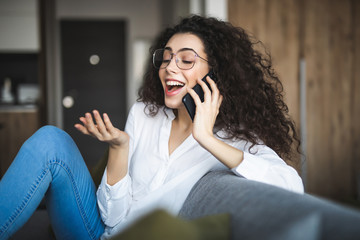 Young woman using mobile phone while sitting on couch at home