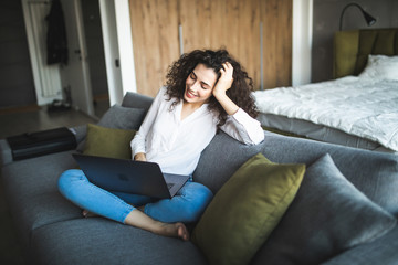 Obraz premium Happy pretty woman using laptop sitting on sofa